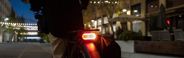 Brake lights on the back of a Radster Trail on a city street at dusk.